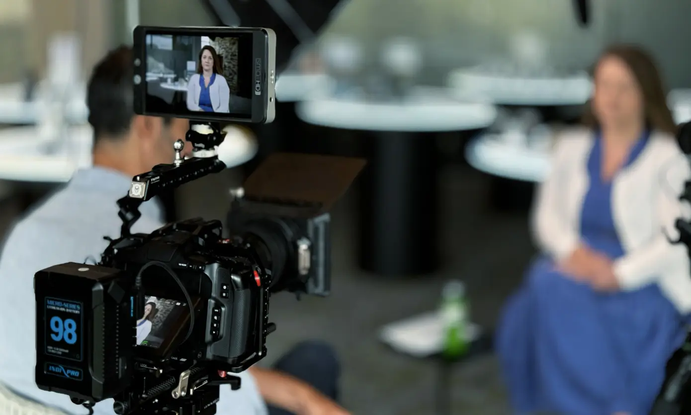 A man is filming an interview with a woman.